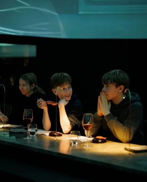 Young guests seated at the chef's counter at Alchemist, watching a course arrive